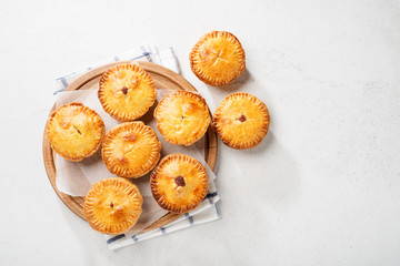 Traditional Australian Mini meat pies from shortbread dough on a light gray background. © Nelea Reazanteva