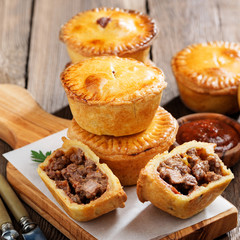 Traditional Australian Mini meat pies from shortbread dough on a wooden board over wooden background. © Nelea Reazanteva