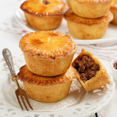 Traditional Australian Mini meat pies from shortbread dough on a white wooden background.