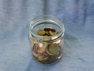 coins spilling out of glass jar on black background