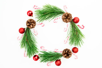 Christmas frame of pine branches and red balls decoration with candy cane on white background. Festive background. Flat lay, top view