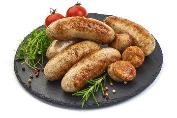 Grilled Munich sausages with herbs and tomatoes on a shale slate plate, isolated on a white background. Close-up.