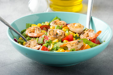 Salad with corn, fried shrimp, cherry tomatoes, red onions and lettuce. Fresh tasty lunch, healthy food