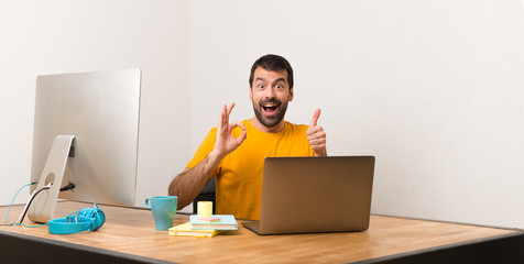 Man working with laptot in a office showing ok sign with and giving a thumb up gesture