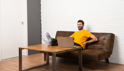 Man with his laptop in a room suffering from backache for having made an effort
