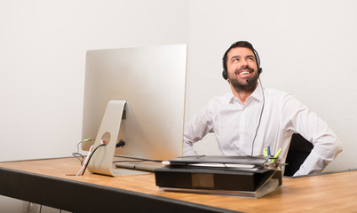 Fototapeta premium Telemarketer man in a office posing with arms at hip and laughing
