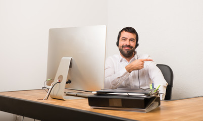 Telemarketer man in a office pointing finger to the side in lateral position
