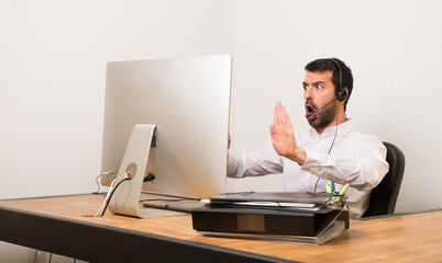 Telemarketer man in a office making stop gesture for disappointed with an opinion