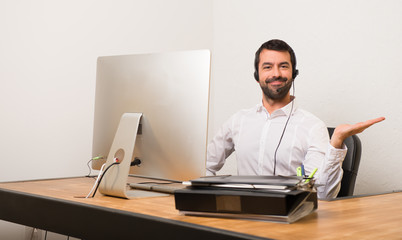 Telemarketer man in a office holding copyspace imaginary on the palm to insert an ad