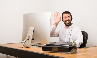Telemarketer man in a office saluting with hand with happy expression