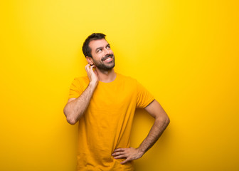 Man on isolated vibrant yellow color thinking an idea while scratching head