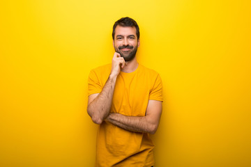Obraz premium Man on isolated vibrant yellow color smiling with a sweet expression