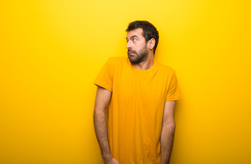 Man on isolated vibrant yellow color is a little bit nervous and scared pressing the teeth