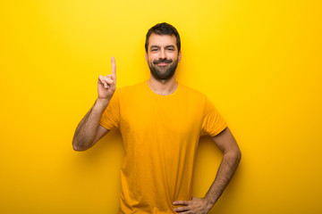 Man on isolated vibrant yellow color showing and lifting a finger in sign of the best