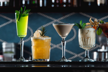 row of various colourfull alcoholic cocktails on a bar desk. Glasses of differen shapes