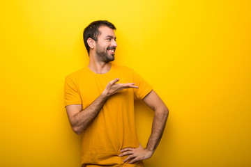Obraz premium Man on isolated vibrant yellow color presenting an idea while looking smiling towards