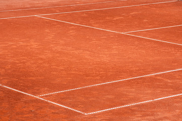 Part of empty used red clay tennis court playground surface with white lines closeup