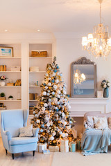 Interior of cozy room decorated in Christmas Happy new Year style. No people. An empty sofa, Christmas tree with presents under it. Selective focus. Happy NY mood