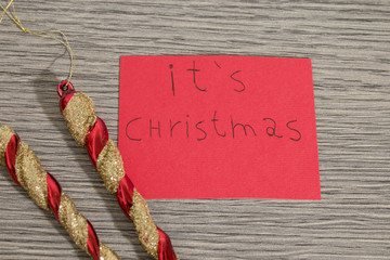 It's christmas write on a red paper with decorations