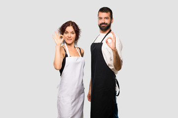 Couple of cooks showing an ok sign with fingers on grey background