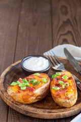 Baked loaded potato skins with cheddar cheese and bacon, garnished with scallions and sour cream, vertical copy space