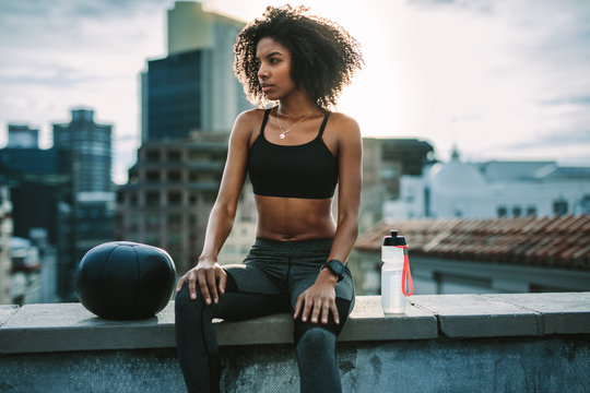 Fitness woman sitting on rooftop relaxing