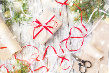 Packing Christmas presents in kraft paper with red and white ribbons