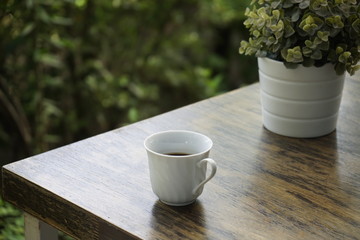 White cup of black coffee on the wooden table in the morning
