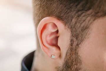 Earring in the male ear. Piercing Part of the body.