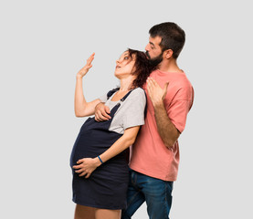 Couple with pregnant woman fainting of childbirth on isolated grey background