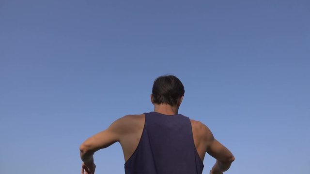 man does physical exercises against the sky, turns the torso. Age forty years.