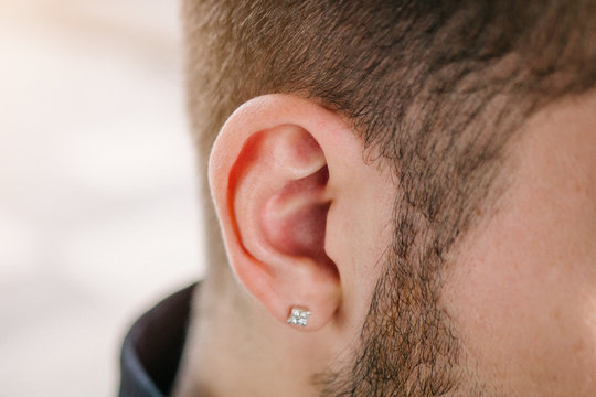 Earring in the male ear. Piercing Part of the body.