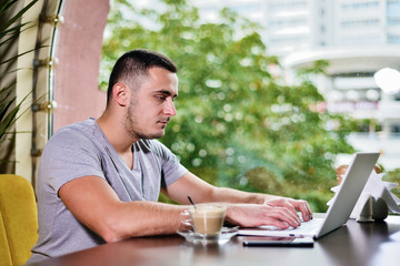 Young guy freelancer working on laptop in cafe