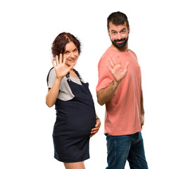 Couple with pregnant woman counting five with fingers on isolated white background