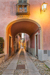 Fototapeta na wymiar Beautiful scenic alley with historic and traditional houses and cobbled street. Picturesque Italian village, Orta San Giulio (street Giovanetti), on lake Orta, north Italy