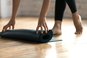 Close up woman hands unrolling mat preparing for fitness workout at gym studio. Sportive female...