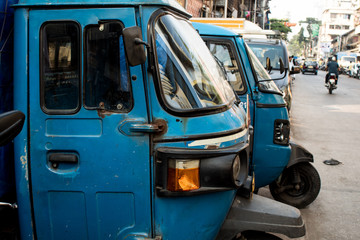 Blue three-wheels vans for little deliveries parked in the streets of Mumbai, India