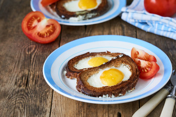 Baked toasts with egg filling and tomato slices on a plate 