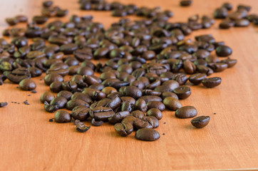 Coffee grains lying on a wooden background.