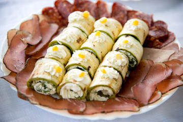 Close up of small canapes arranged on a plate over light background - selective focus