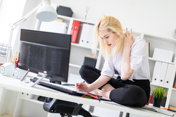 A young girl sitting on a Desk in the office and working with documents and computer.
