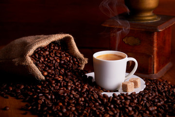Cup of espresso with coffee beans and old ginger on wooden table