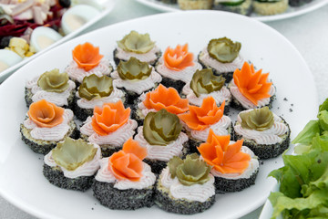 Close up of small canapes arranged on a plate over light background - selective focus