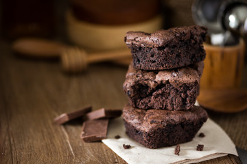 A stack of chocolate brownies on wooden background with mint leaf on top, homemade bakery and...