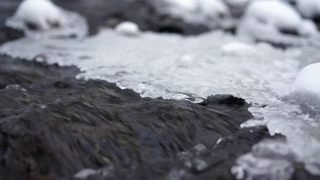 The cold river flows turning into a crust of transparent ice in the autumn evening, close-up.4k,30fps