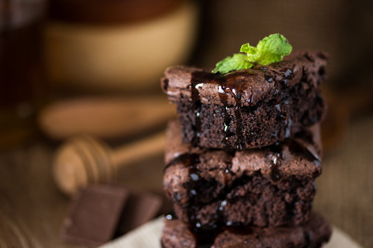A stack of chocolate brownies on wooden background with mint leaf on top, homemade bakery and dessert