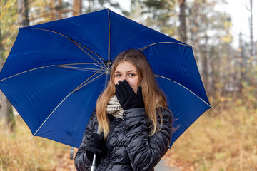 Attractive young elegant girl walking in the park with umbrella
