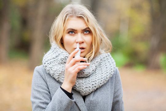 Cold And Flu. Young Sick Woman Uses A Nose Spray At Street Outside