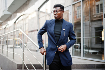 Amazingly looking african american man wear at blue blazer with brooch, black turtleneck and glasses posed at street. Fashionable black guy.