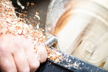 closeup of rotating wood and hand with turnery and flying sawdust shavings